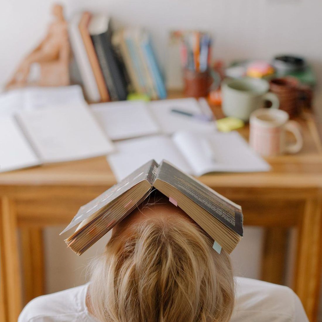 Student resting under an open textbook